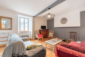 Een woonkamer met een bank, fauteuil, salontafel en televisie.