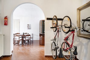 Zona pranzo con tavolo e sedie, una bicicletta appesa al muro e un estintore.