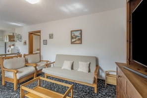 A living room with a sofa, two armchairs, a coffee table, a television, and a kitchen area in the background. - Holiday Home 'Aguarijo' with Sea View, Private Terrace and Private Garden (El Mocanal)