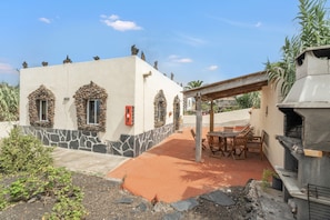 A building with stone accents, a barbecue area, and outdoor seating. - Holiday Home 'Aguarijo' with Sea View, Private Terrace and Private Garden (El Mocanal)