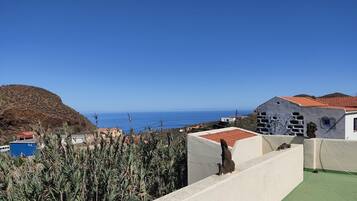 Vista costera con edificios, cielo despejado y una montaña distante.