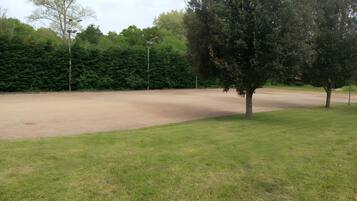 Un campo cubierto de césped, con árboles y un sendero de tierra.