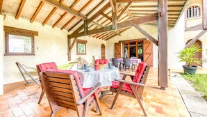 Un patio al aire libre con mesa y sillas de madera, una hamaca y una planta en maceta.