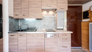 Une cuisine moderne avec des meubles en bois, un évier en acier inoxydable et un lave-vaisselle encastré.