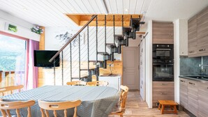 Une cuisine moderne avec des meubles en bois, un four encastré et un réfrigérateur en acier inoxydable.