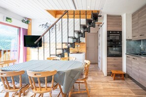 A modern kitchen with wooden cabinets, a built-in oven, and a stainless steel refrigerator.