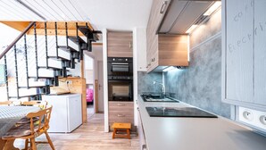 Une cuisine moderne dotée d’un four encastré, un coin repas avec des meubles en bois et un escalier menant à un autre niveau.