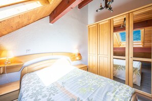 Quarto com cama, guarda-roupa de madeira e claraboia.