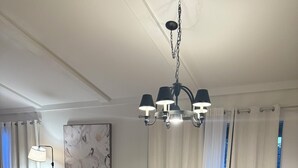 Een eetruimte met een houten tafel, stoelen, een kroonluchter en een potplant.