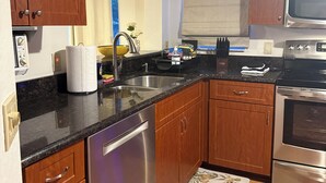 Een moderne keuken met houten kastjes, roestvrijstalen apparatuur en een betegelde achterwand.