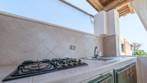 Una cocina con estufa a gas, un lavamanos y un protector contra salpicaduras de azulejos.