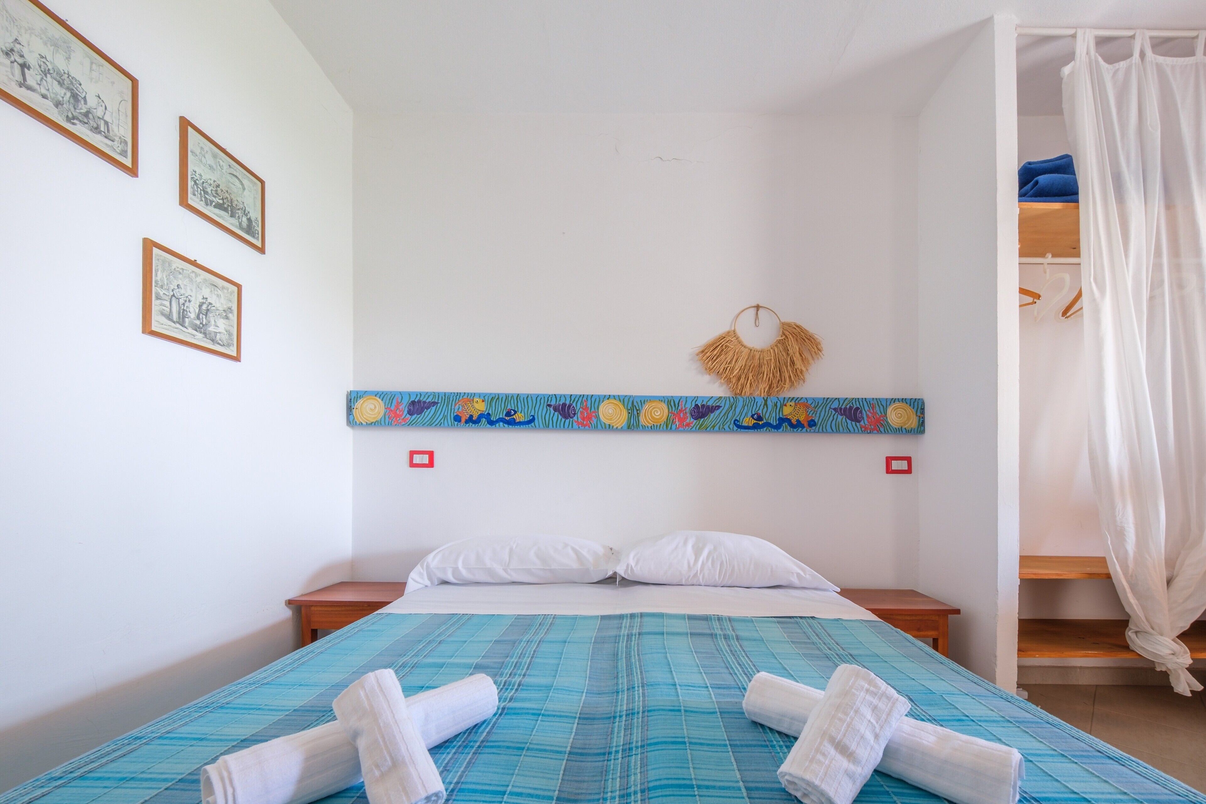 A bedroom with a bed, white pillows, a blue-striped bedspread, and rolled towels.