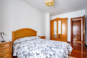 A bedroom with a wooden bed, a nightstand, a dresser, and a wardrobe.