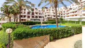 A residential building with multiple balconies, a swimming pool, and palm trees. - 'Incredible Playazo Vera' Apartment with Shared Pool, Private Terrace & Air Conditioning (Vera)