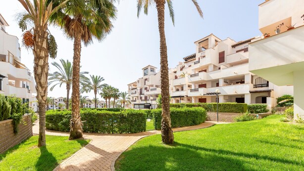 A residential area with multi-story buildings, palm trees, and a paved walkway. - 'Incredible Playazo Vera' Apartment with Shared Pool, Private Terrace & Air Conditioning (Vera)