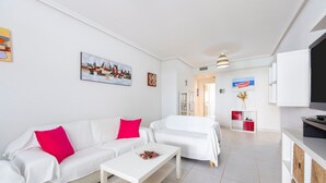A modern living room with white sofas, a coffee table, and artwork on the walls. - 'Incredible Playazo Vera' Apartment with Shared Pool, Private Terrace & Air Conditioning (Vera)