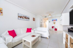 Una sala de estar moderna con sofás blancos, una mesa de centro y obras de arte en las paredes.