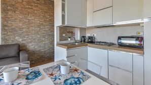 A modern kitchen with a stone wall, a dining table with a clear glass top, and a built-in toaster.