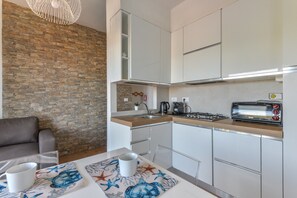 A modern kitchen with a stone wall, a dining table with a clear glass top, and a built-in toaster.