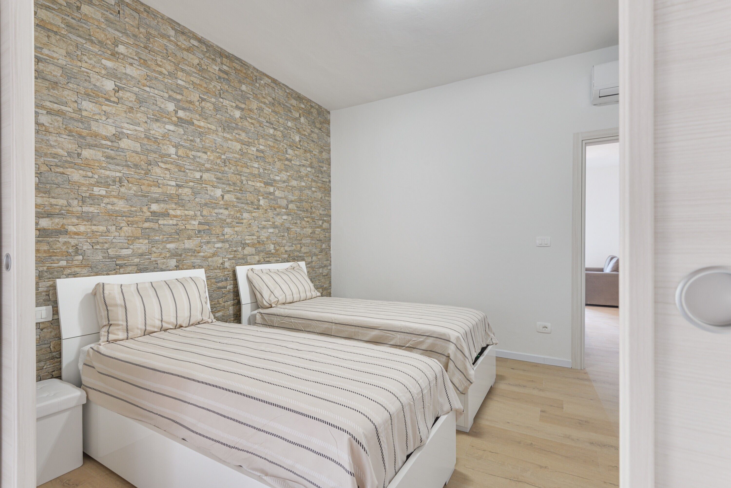 Ein Schlafzimmer mit zwei Betten, einer Steinwand und Holzboden.