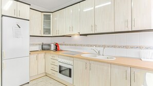 A kitchen with white cabinets, a refrigerator, a microwave, a stove, and a sink.