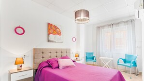 A bedroom with a bed, nightstands, a lamp, a painting, a ceiling light, and two chairs.