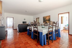 A dining area with a round table, chairs, and a television. - Country House 'Casa Da Quinta' with Mountain View, Private Pool and Wi-Fi (Cepões)
