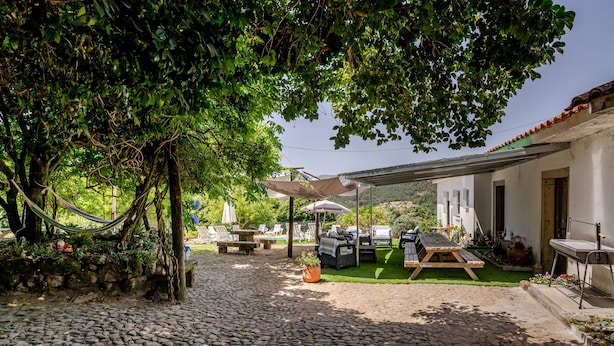 Un patio con sendero adoquinado, mobiliario exterior y una zona cubierta con sombrillas.