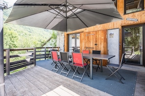 A wooden deck with a table and chairs, a large umbrella, and a 'BIENVENUE' sign.