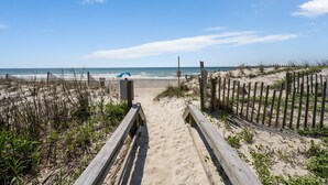 A sandy beach with wooden walkways leading to the water, a wooden fence, and sparse vegetation. - Clean & Updated Just Steps from the Beach. Dogs Welcome. Grill & Beach Gear (Surf City)