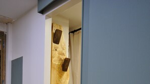 Una stanza con una porta in legno, un interruttore della luce e una tenda.