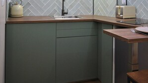 Una cucina compatta con backsplash in piastrelle a spina di pesce, lavastoviglie integrata e un piccolo oblò sopra il lavello.