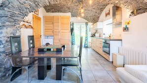 Una cocina moderna con techo de piedra, armarios de madera y un comedor con mesa y sillas de vidrio.
