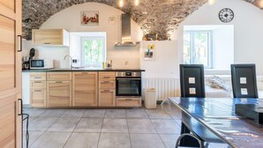 Una cocina con armarios de madera, una estufa y un comedor con mesa y sillas.