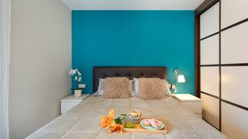 Un dormitorio moderno con una pared de acento color verde azulado, un cabecero capitonado y una mesita de noche con una lámpara.