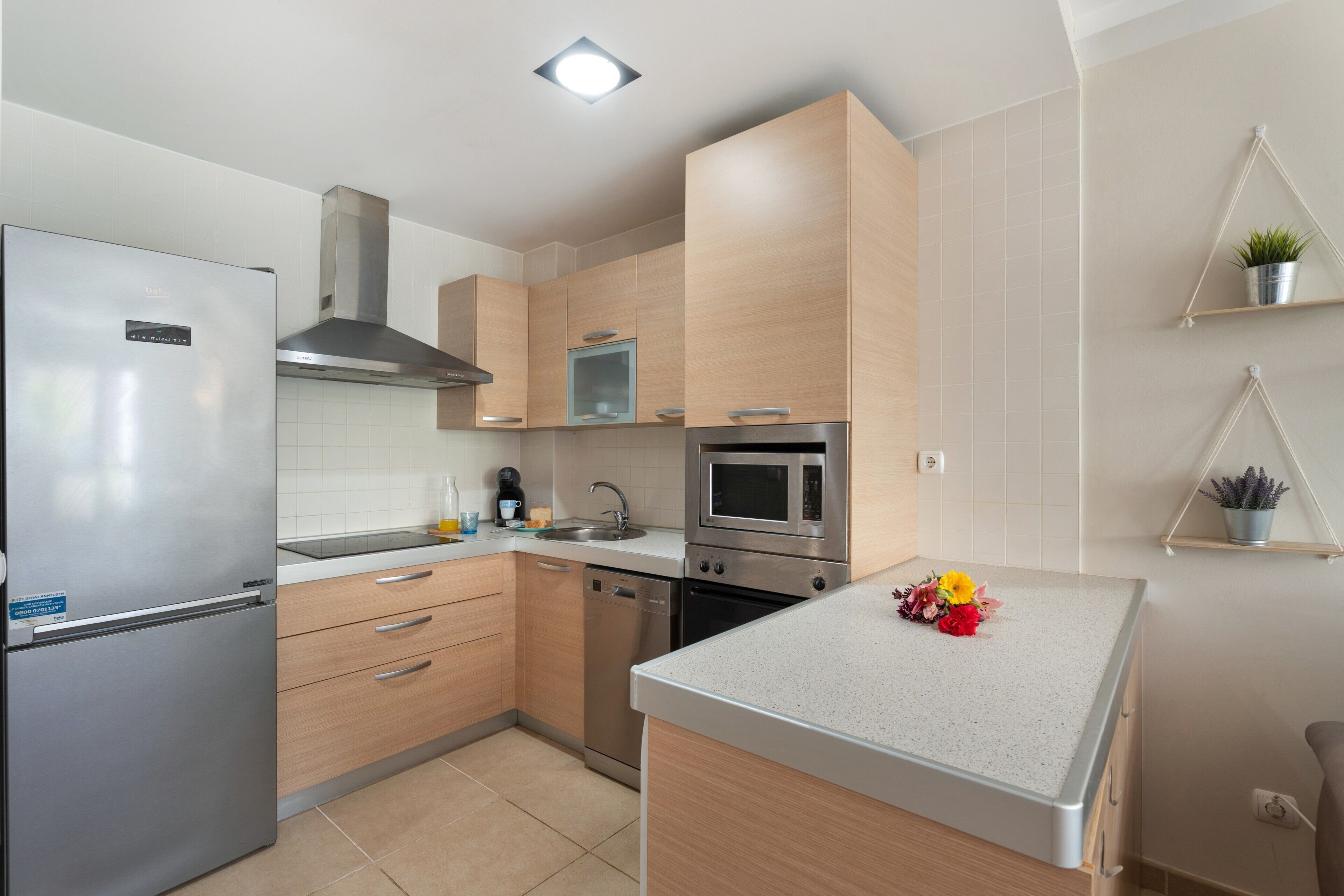 Een moderne keuken met een inbouwoven, magnetron en een koelkast van roestvrij staal.