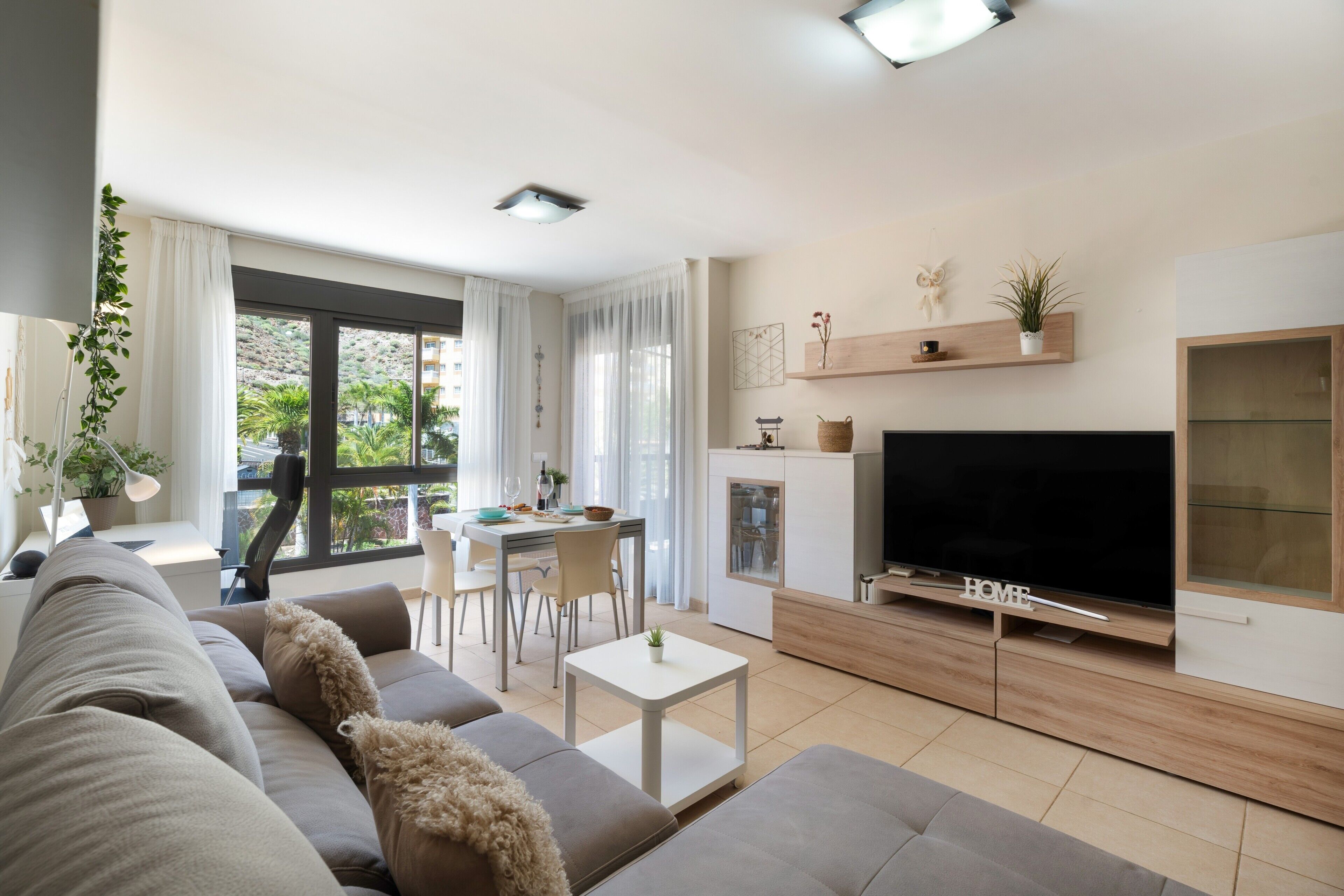 Una sala de estar moderna con sofá, televisor y comedor.