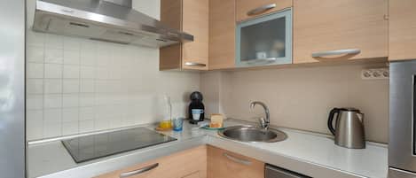 A modern kitchen with stainless steel appliances, wooden cabinets, and a built-in microwave.
