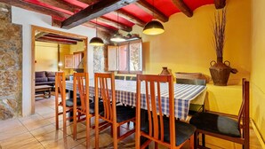 A dining area with wooden chairs and a table, stone walls, and a red ceiling. - Country House 'Caltiku' with Mountain View, Private Pool and Private Terrace (els Ranxos de Bonany)