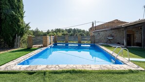 A rectangular swimming pool with stone edges, surrounded by a well-maintained lawn and a stone building with a tiled roof. - Country House 'Caltiku' with Mountain View, Private Pool and Private Terrace (els Ranxos de Bonany)
