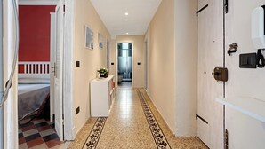 A hallway with a checkered floor, a bed, a white cabinet, and a door with a security camera. - La Casa Di Licia - Apartment in La Spezia (La Spezia)