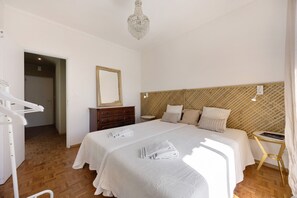 A bedroom with a large bed, a wooden headboard, a bedside table, a mirror, and a hanging light fixture.