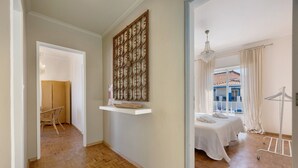 A room with a bed, a wooden floor, a white wall, a hanging light fixture, and a window with curtains. - Apartment 'Regato' with Private Terrace, Balcony and Wi-Fi (Ferragudo)