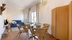 A dining area with wicker chairs, a glass table, and a chandelier. - Apartment 'Regato' with Private Terrace, Balcony and Wi-Fi (Ferragudo)