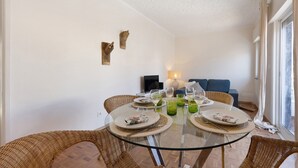 A dining area with a glass table, wicker chairs, and a sofa in the background. - Apartment 'Regato' with Private Terrace, Balcony and Wi-Fi (Ferragudo)
