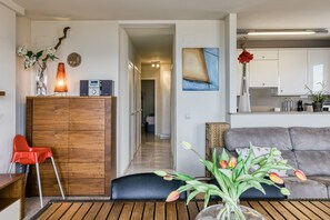 Una sala de estar moderna con un mueble de madera, una silla roja, un sofá negro y un jarrón con flores.