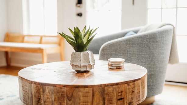 A round wooden table with a white pot and a stack of wooden coasters. - Swans Rest Townhouse, Close to Beach & Restaurants (Cape Charles)