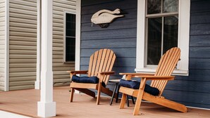 Two wooden Adirondack chairs on a porch with a window and a wall-mounted decoration. - Swans Rest Townhouse, Close to Beach & Restaurants (Cape Charles)