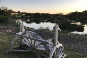 A wooden chair by a calm lake at sunset. - Foxglove - Barn Conversion - Blossom Farm (Haverfordwest)