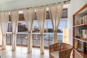 A room with large windows, a wicker chair, and a bookshelf. - Vacation 'Las Velas' with Sea View, Wi-Fi and Air Conditioning (Gáldar)